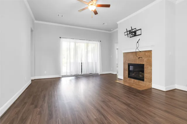 an empty room with wooden floor chandelier fan and windows