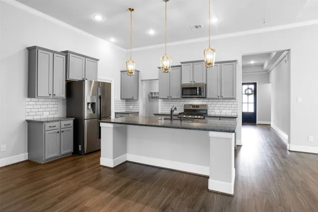 a large kitchen with stainless steel appliances kitchen island granite countertop a refrigerator a stove a sink and a microwave