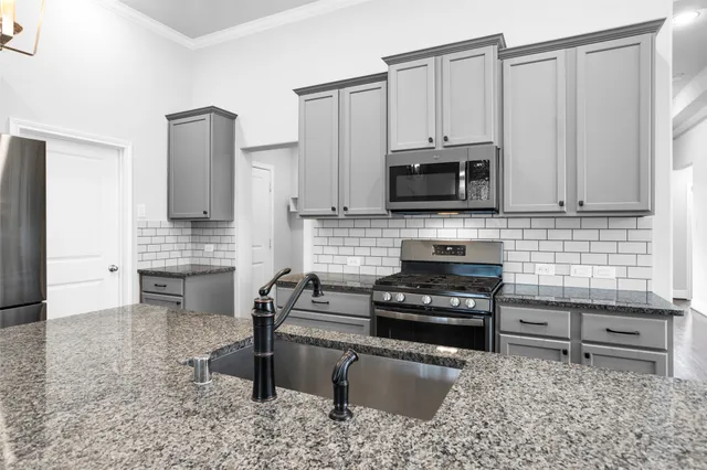 a kitchen with granite countertop a stove a sink and a microwave