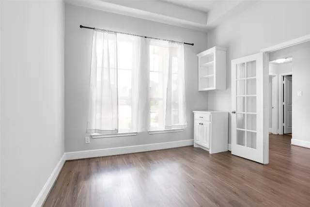a view of empty room with wooden floor and fan