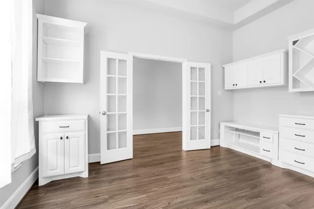 an empty room with wooden floor and cabinet