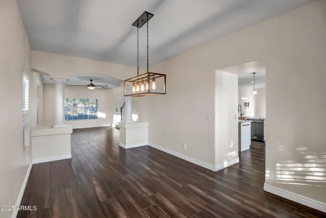 a view of a big room with wooden floor a kitchen and windows