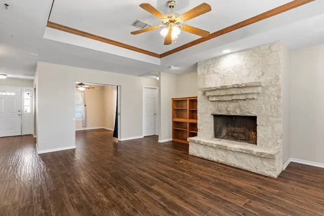 a view of an empty room with wooden floor fireplace and a window