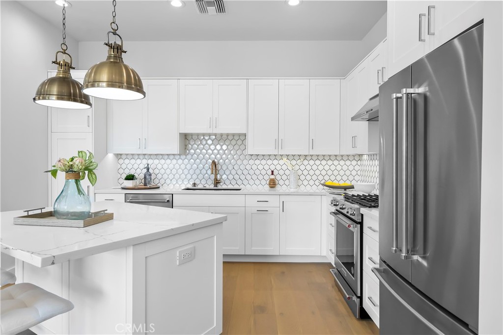 2317 Vanderbilt Lane, Unit A Redondo Beach, CA 90278 - Photo 5 of 39 a kitchen with stainless steel appliances granite countertop a refrigerator a sink dishwasher a stove a dining table and chairs with wooden floor