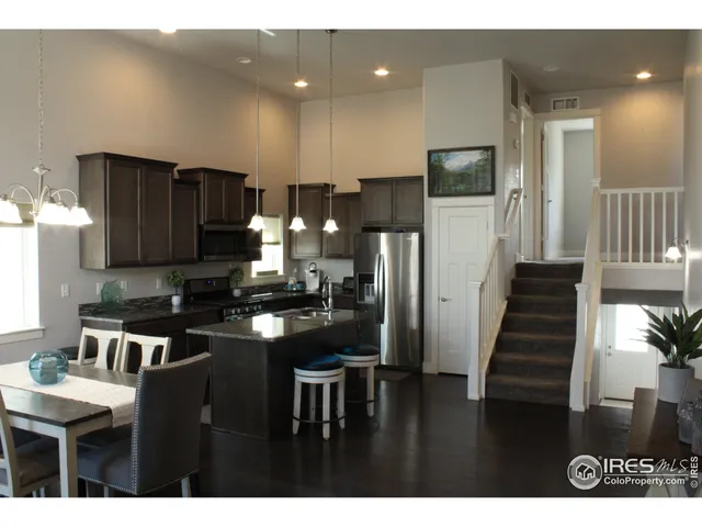 a kitchen with stainless steel appliances kitchen island granite countertop a refrigerator a stove a sink and a microwave with wooden floor