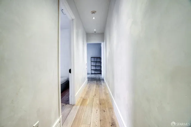 a view of a hallway with wooden floor and closet