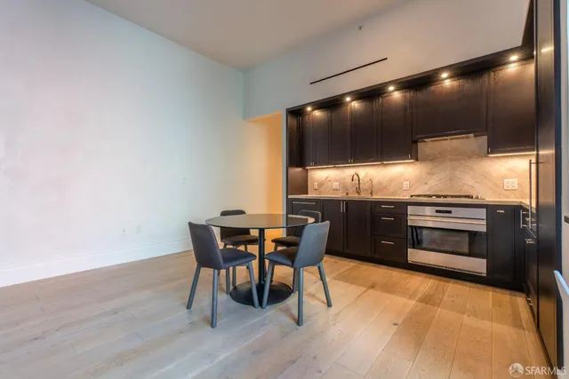 a kitchen with stainless steel appliances a table chairs and wooden floor