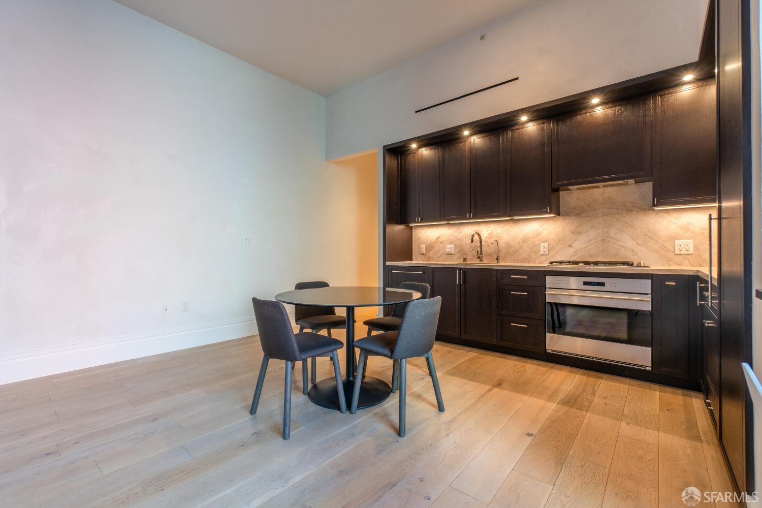 288 Pacific Avenue, Unit 2F San Francisco, CA 94111 - Photo 19 of 34 a kitchen with stainless steel appliances a table chairs and wooden floor