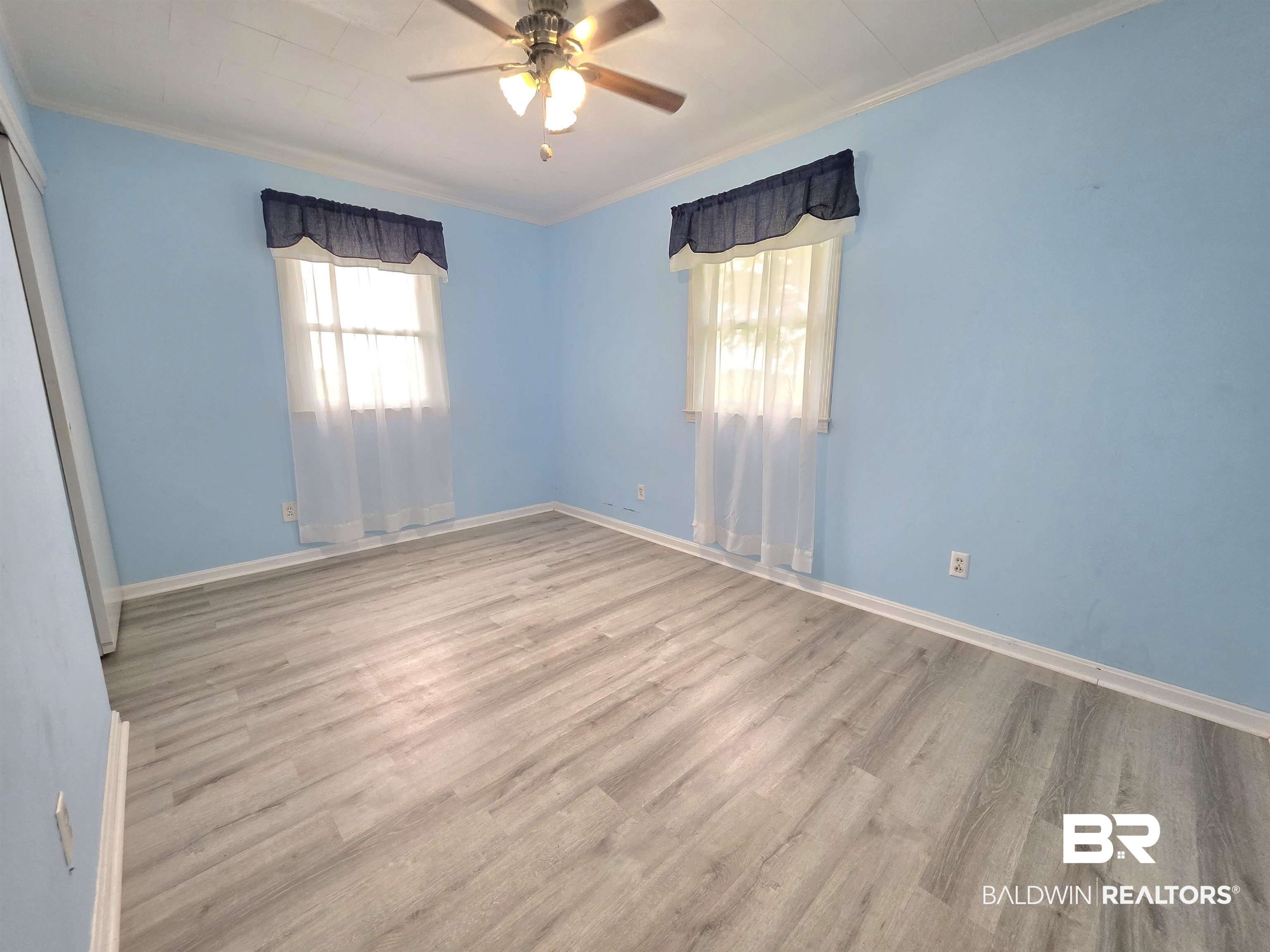 558 Stanton Road Atmore, AL 36502 - Photo 15 of 29 Spacious room featuring wood-finish flooring, two windows, crown molding, and a ceiling fan