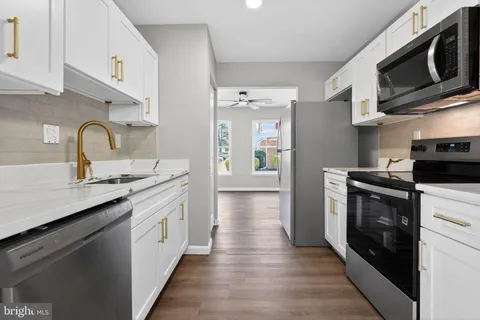 a kitchen with stainless steel appliances granite countertop a sink and a stove top oven with wooden floor