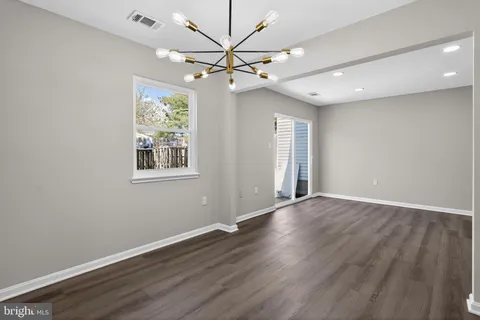 an empty room with wooden floor chandelier fan and windows