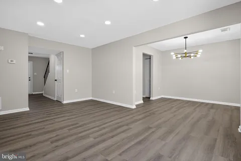 a view of an empty room with wooden floor and chandelier