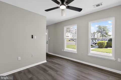 a view of an empty room with a window and wooden floor