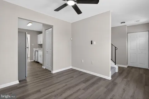 a view of an empty room with wooden floor and a ceiling fan