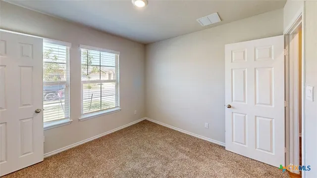 an empty room with wooden floor ceiling fan and windows