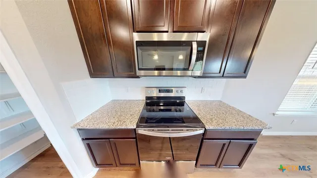 a kitchen with stainless steel appliances granite countertop a sink a stove top oven a counter space and cabinets