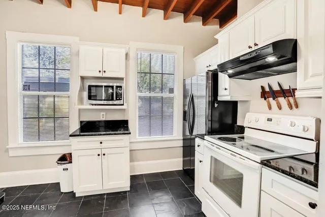 a kitchen with white cabinets and appliances
