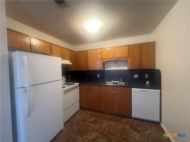 a kitchen with stainless steel appliances granite countertop a refrigerator and a stove