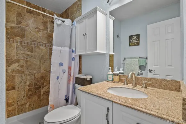 a bathroom with a granite countertop sink toilet and shower