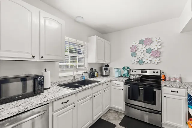 a kitchen with granite countertop white cabinets and white appliances
