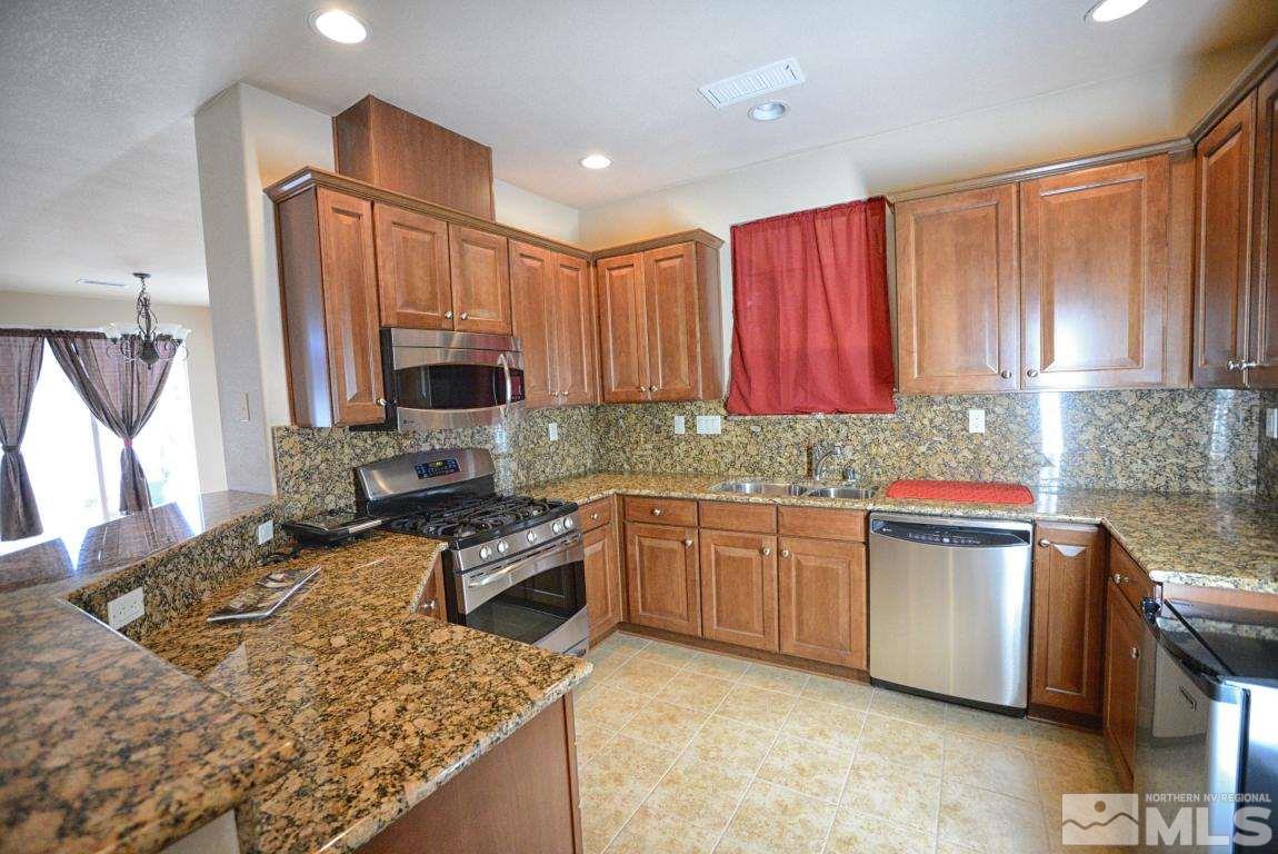 1897 Resistol Drive Reno, NV 89521 - Photo 4 of 9 a kitchen with stainless steel appliances granite countertop sink stove top oven and cabinets