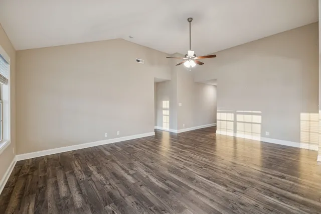 an empty room with wooden floor and windows
