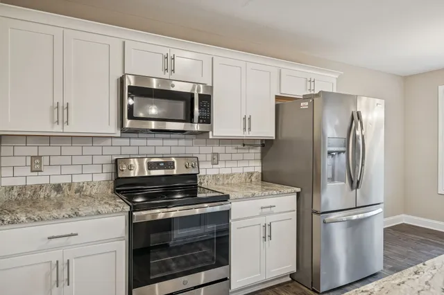 a kitchen with granite countertop a refrigerator stove and microwave
