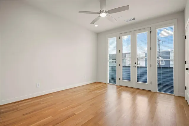 an empty room with wooden floor fan and windows