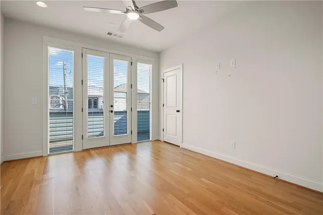 an empty room with wooden floor and fan