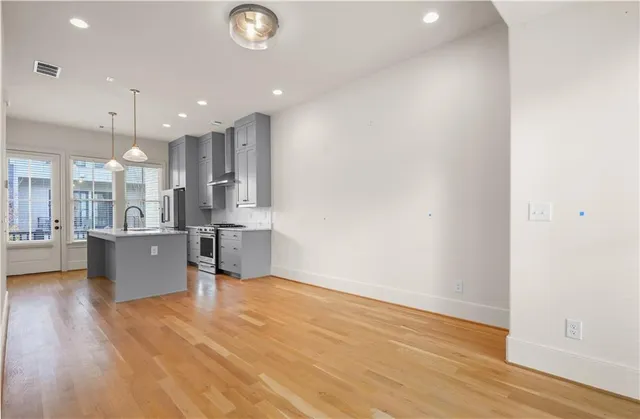 a view of kitchen with kitchen island a sink wooden floor and stainless steel appliances