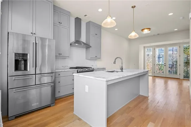 a kitchen with a sink stainless steel appliances a large window and wooden floor