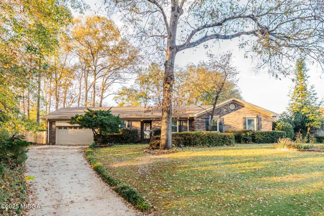 a front view of a house with a yard and trees