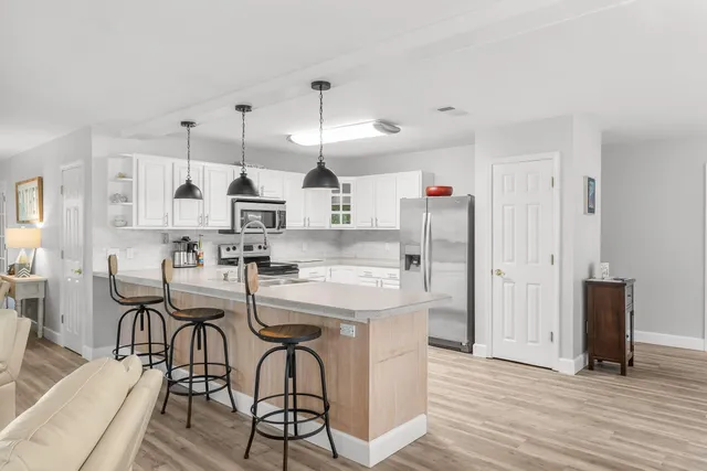 a kitchen with granite countertop a sink stainless steel appliances and white cabinets