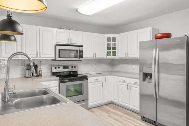 a kitchen with a sink stainless steel appliances and white cabinets