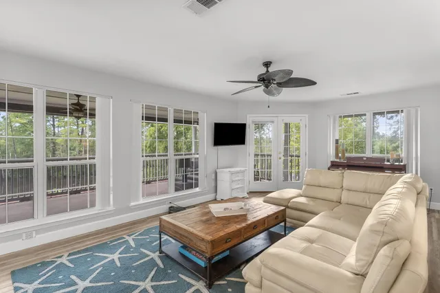 a living room with furniture ceiling fan and a large window