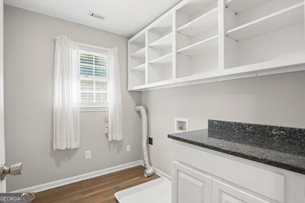 an empty room with wooden floor ceiling fan and windows