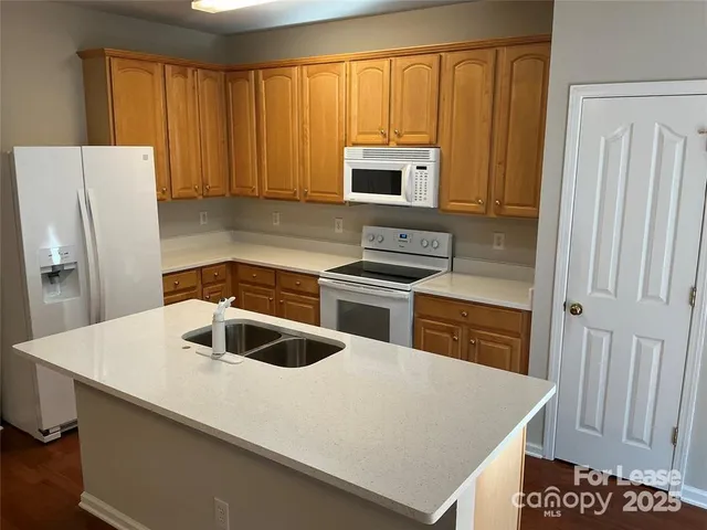 a kitchen with granite countertop a sink a stove and refrigerator