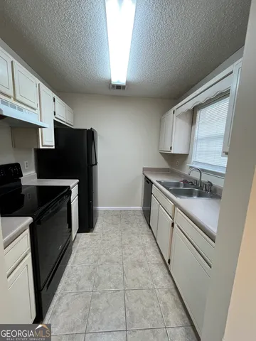 a kitchen with granite countertop a refrigerator and a stove top oven