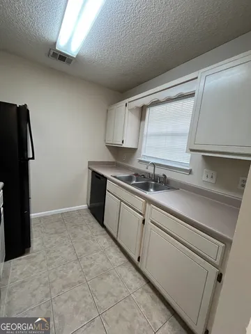 a kitchen with a sink a refrigerator and cabinets