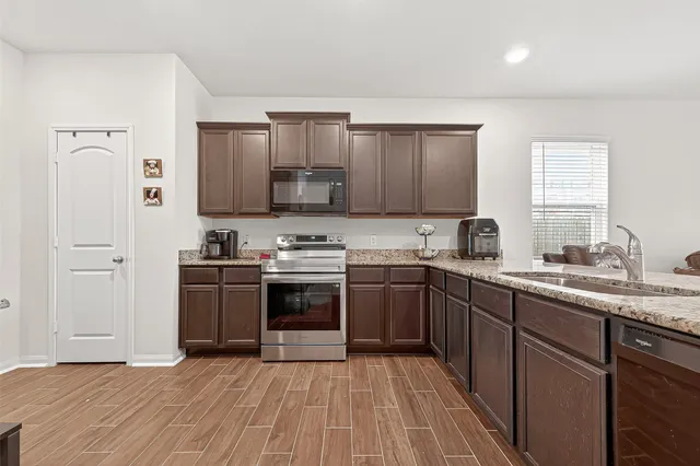 a kitchen with stainless steel appliances granite countertop a stove a sink and a refrigerator