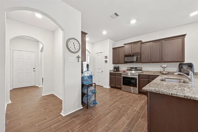 a kitchen with granite countertop a stove a sink and a refrigerator