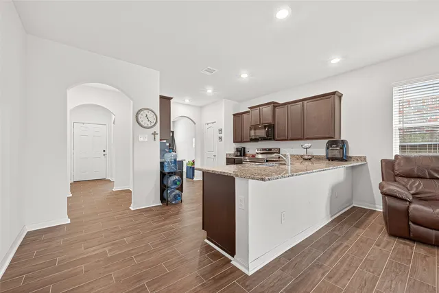 a kitchen with stainless steel appliances granite countertop a stove top oven a refrigerator a sink and a microwave