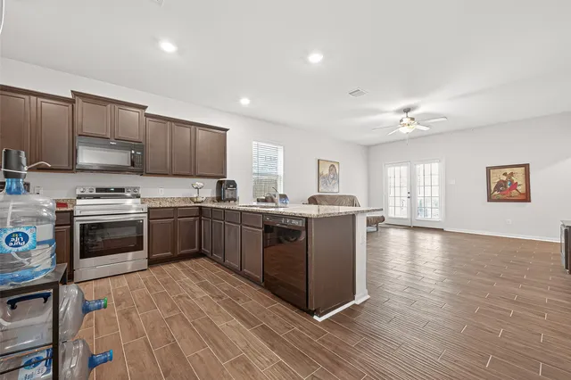 a kitchen with stainless steel appliances a stove a sink dishwasher a refrigerator and a microwave oven with wooden floor