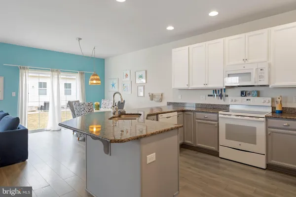 a kitchen with kitchen island granite countertop a sink cabinets and wooden floor