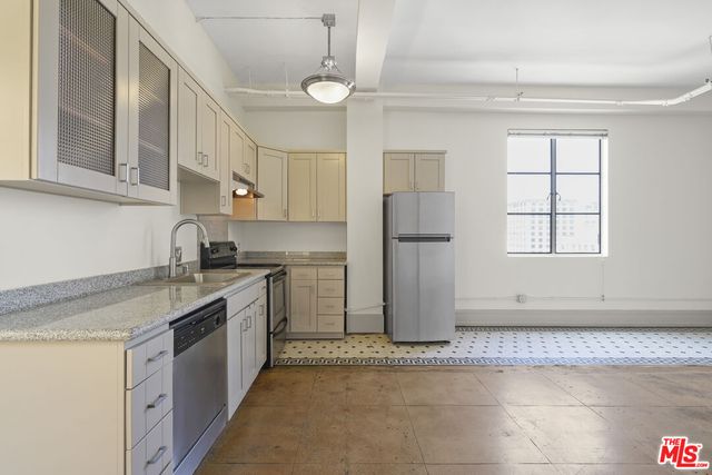a kitchen with granite countertop a refrigerator and a stove top oven