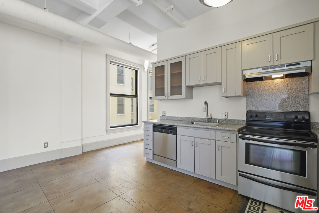 108 West 2nd Street, Unit 708 Los Angeles, CA 90012 - Photo 15 of 40 a kitchen with granite countertop a stove sink and cabinets