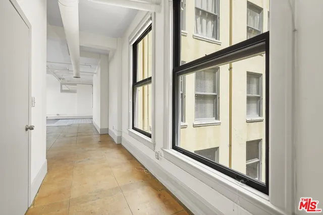 an empty room with an entryway and chandelier fan