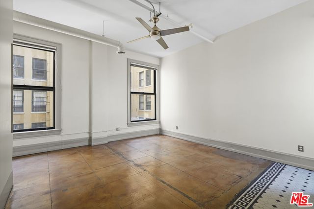 an empty room with windows and fan