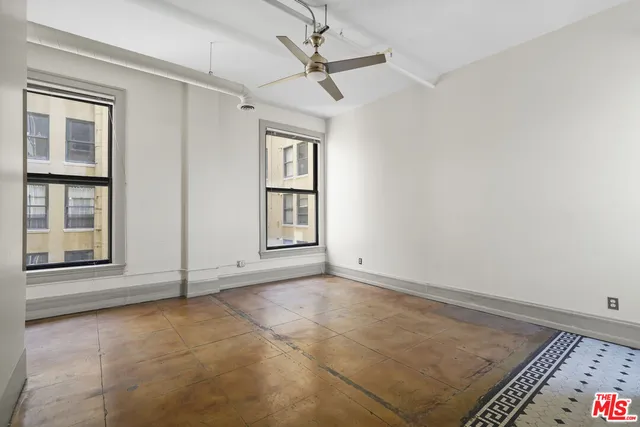 an empty room with windows and fan