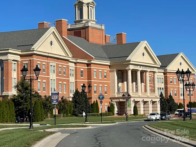a view of a white house next to a yard with big trees